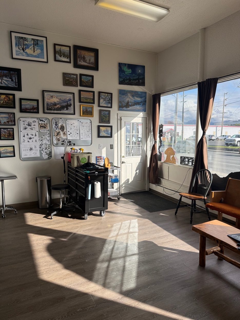 AK Tattoo Anchorage interior — Alaska paintings on the wall natural light tattoo studio